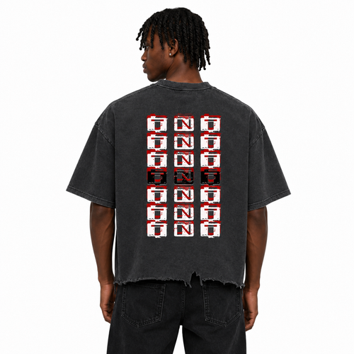 Rear view of a Black male model wearing the Trini Born Culture Tee in vintage black featuring the signature TNT-inspired back graphic, oversized boxy fit with cropped distressed hem on a white studio background.