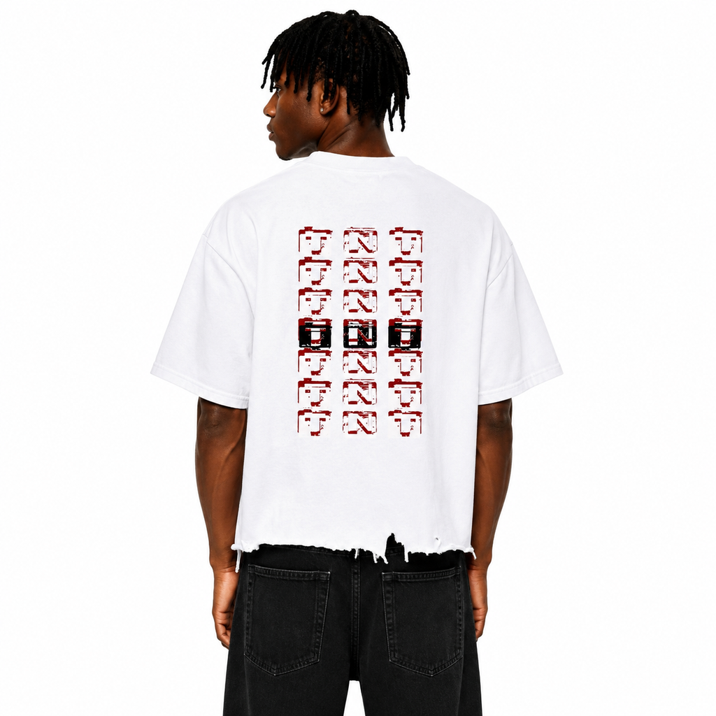 Rear view of a Black male model wearing the Trini Born Culture Tee in white featuring the signature red, black, and white TNT-inspired back graphic, oversized boxy cropped fit with distressed hem on a clean white studio background.