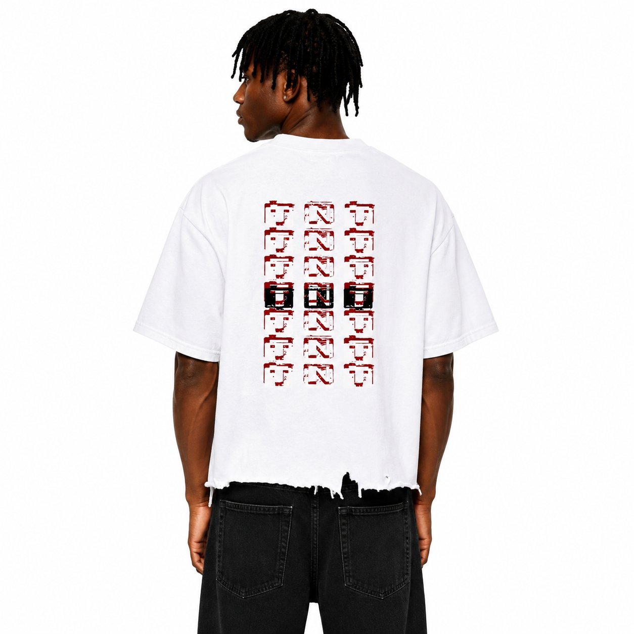 Rear view of a Black male model wearing the Trini Born Culture Tee in white featuring the signature red, black, and white TNT-inspired back graphic, oversized boxy cropped fit with distressed hem on a clean white studio background.