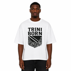Black male model wearing the Trini Born oversized white graphic T-shirt with bold black crest design, boxy fit, premium cotton, front view on a white studio background.