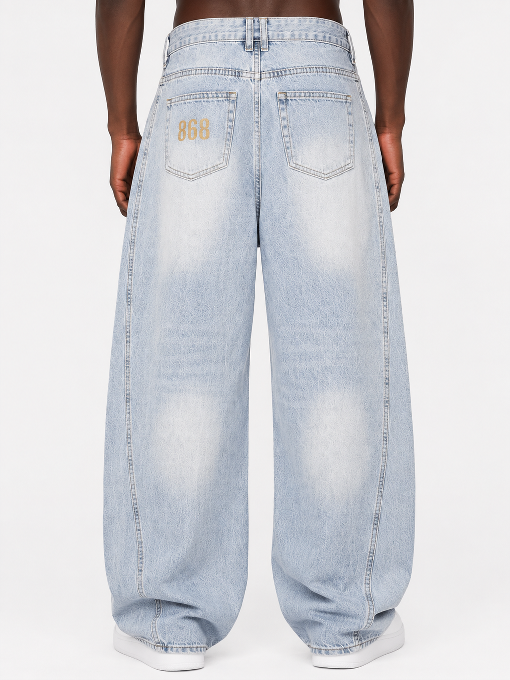 Back view of Black male model wearing Trini Born vintage wash barrel leg jeans in light blue with 868 pocket graphic and a loose barrel-leg fit.