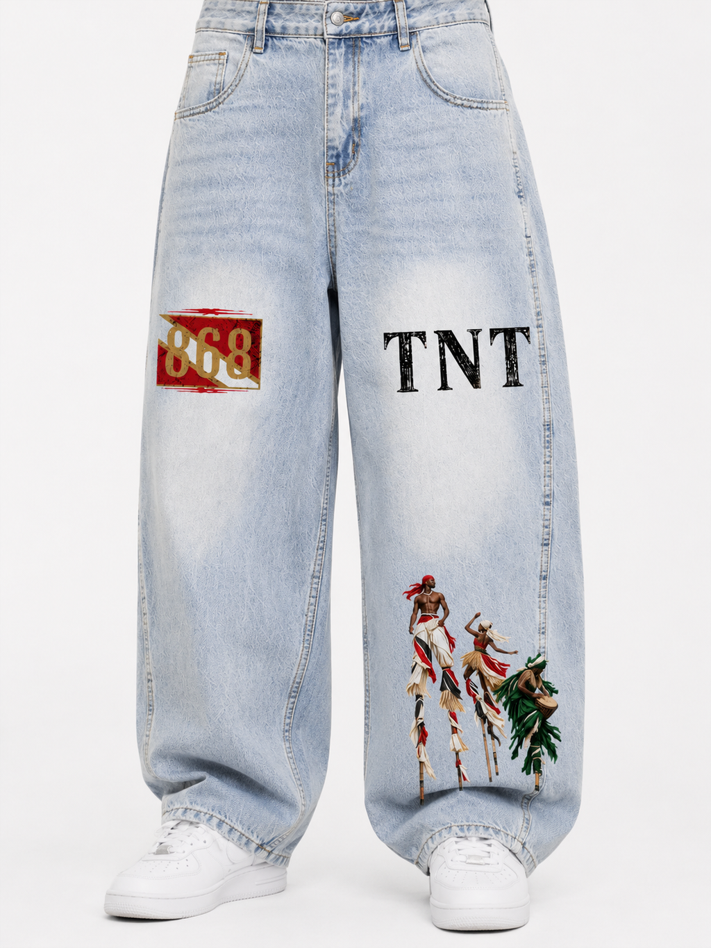 Black male model wearing Trini Born vintage wash barrel leg jeans in light blue, front view with 868, TNT, and Trinidad carnival stilt performer graphics.